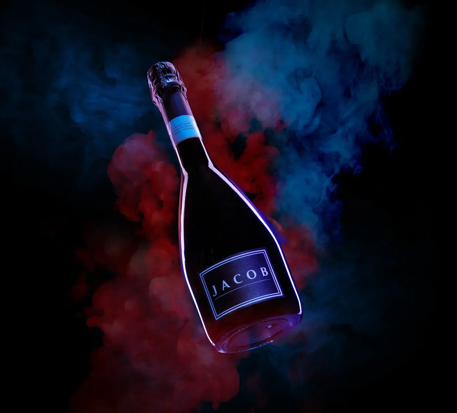 The bottle standing in red and blue dry-ice smoke, label glowing cyan